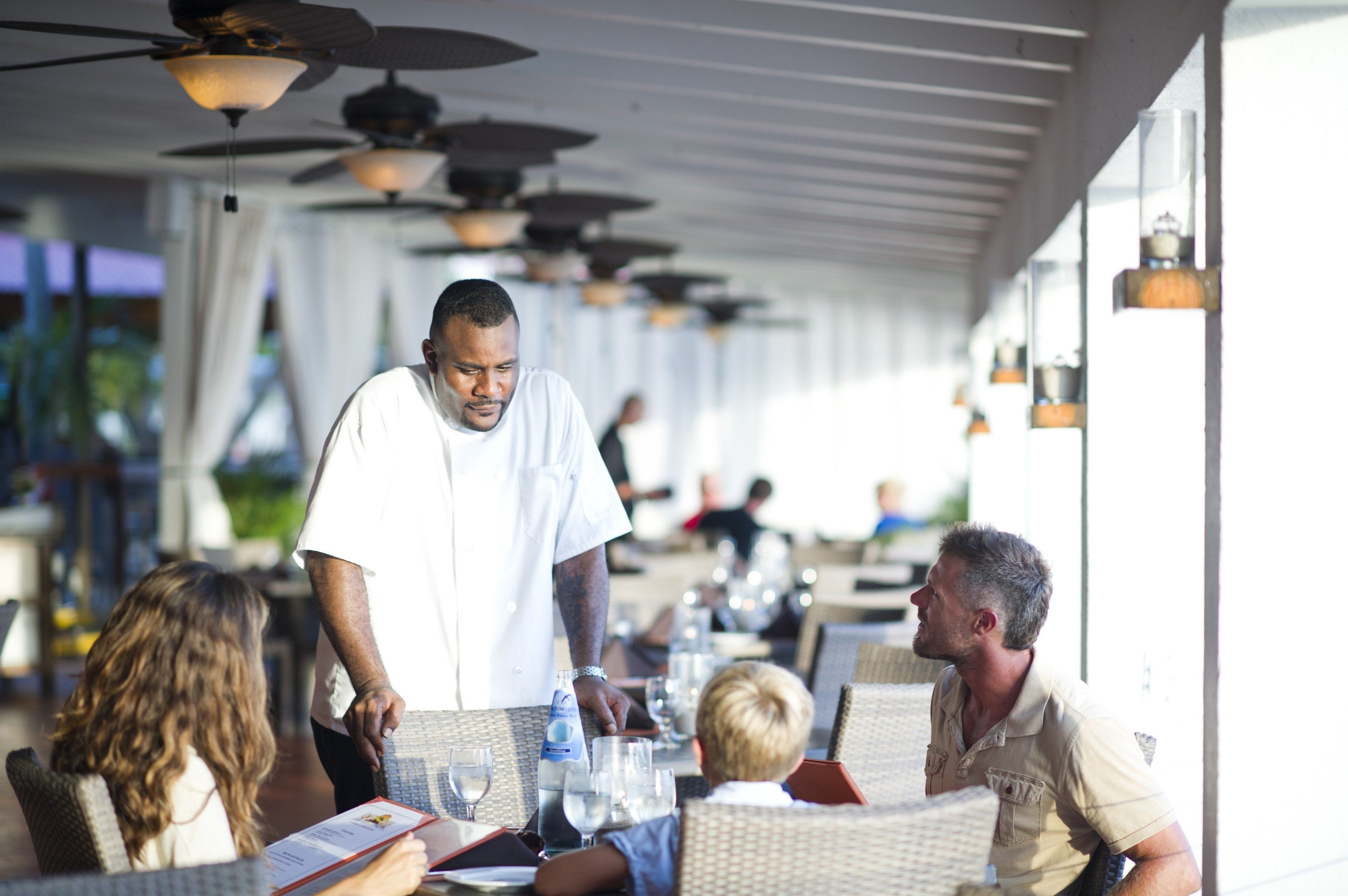 Un restaurant doté d’une terrasse, de ventilateurs de plafond et de lanternes suspendues.