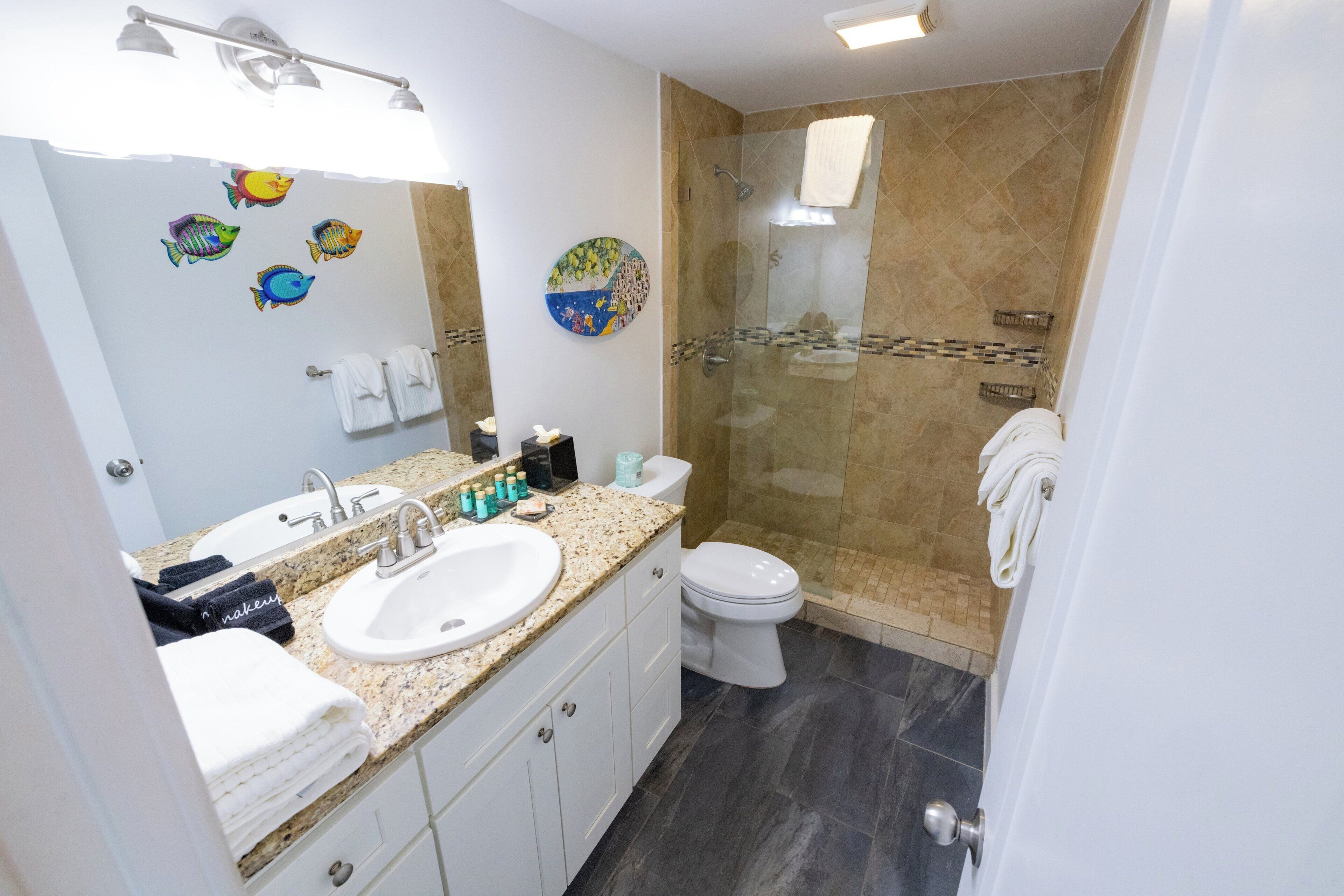 Un baño con lavamanos, inodoro y zona de ducha.