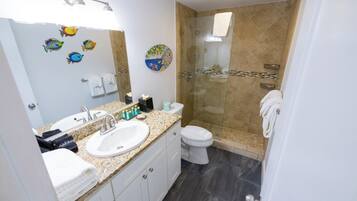 Un baño con lavamanos, inodoro y zona de ducha.