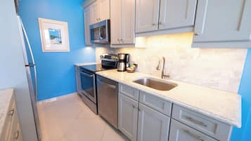 A kitchen with white cabinets, a stainless steel sink, a microwave, and a coffee maker.