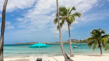 Aan het strand, wit zand, ligstoelen aan het strand, parasols