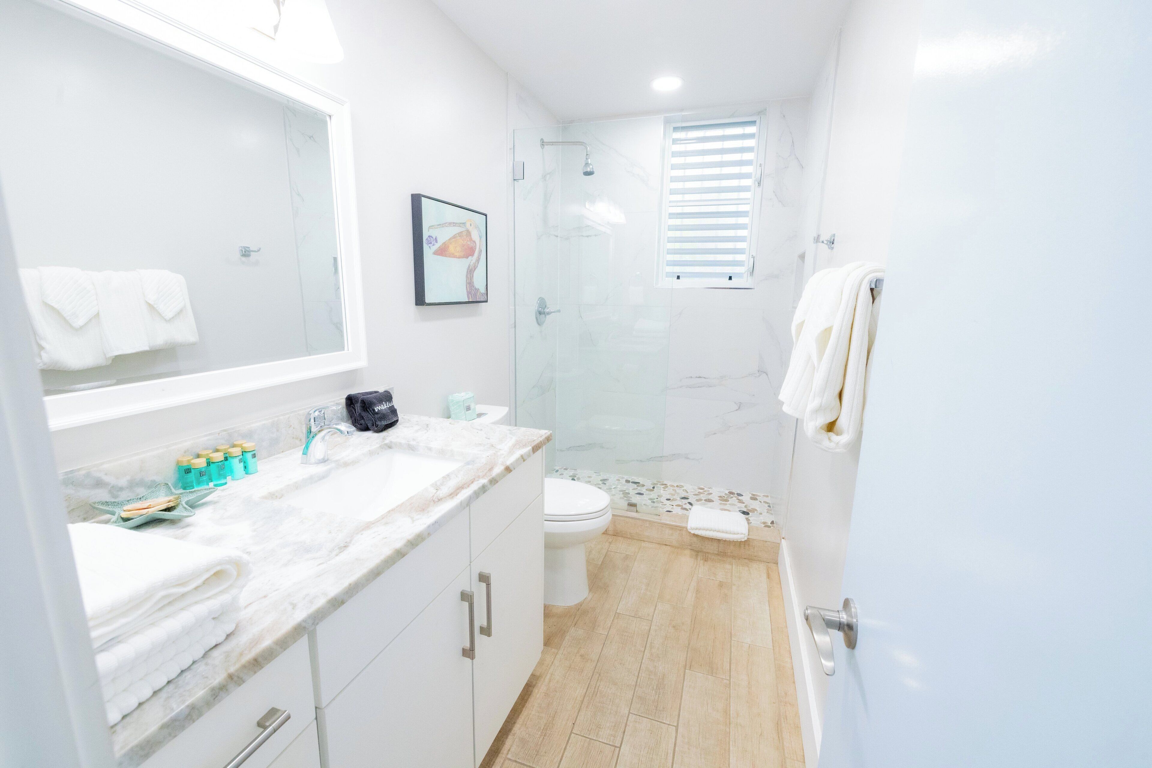 A modern bathroom with a glass shower enclosure, a marble countertop, and a white toilet.