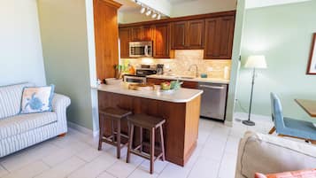A modern kitchen with wooden cabinets, a central island with stools, a microwave, and a coffee maker.