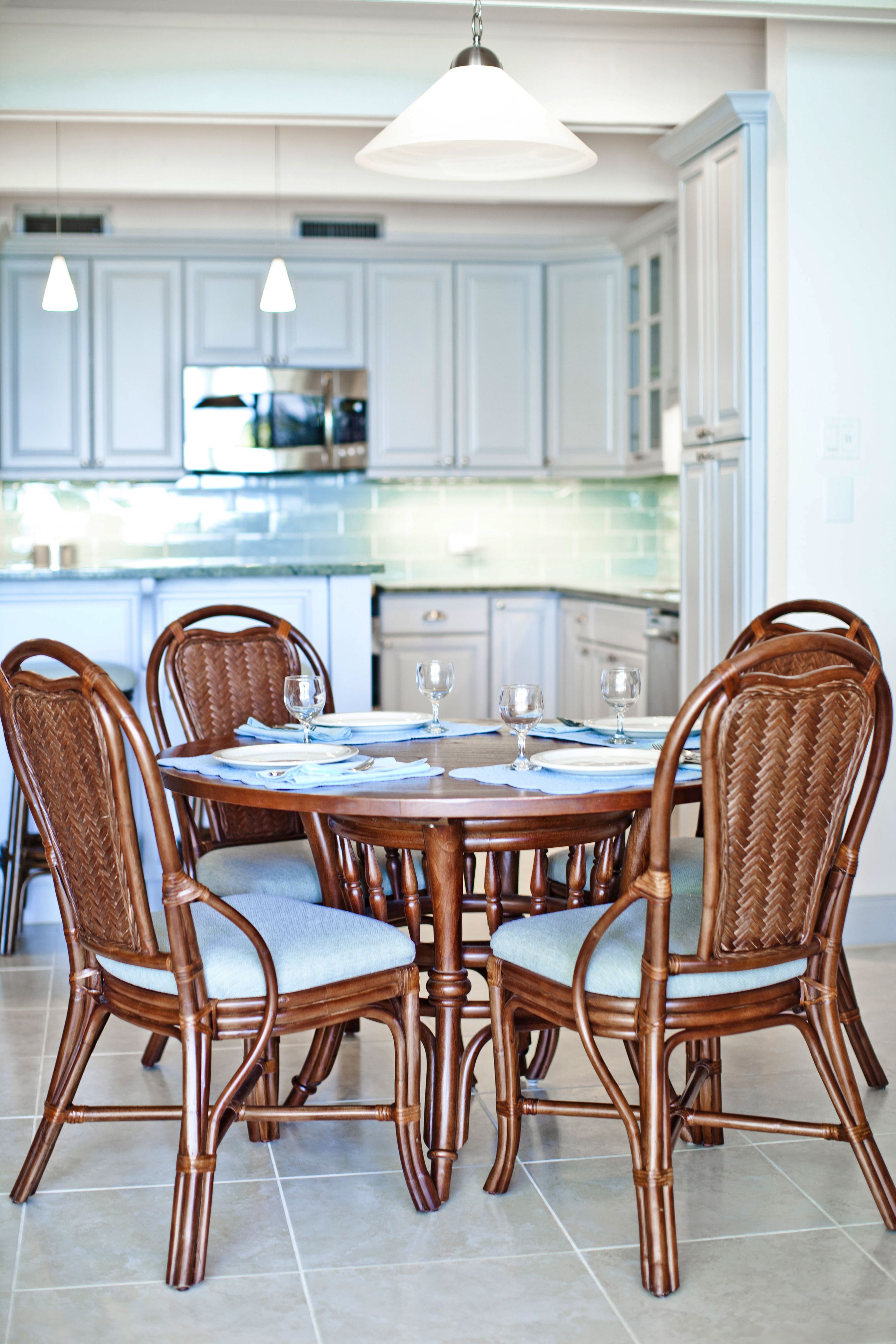 A dining area with a round table, four chairs, and a chandelier.