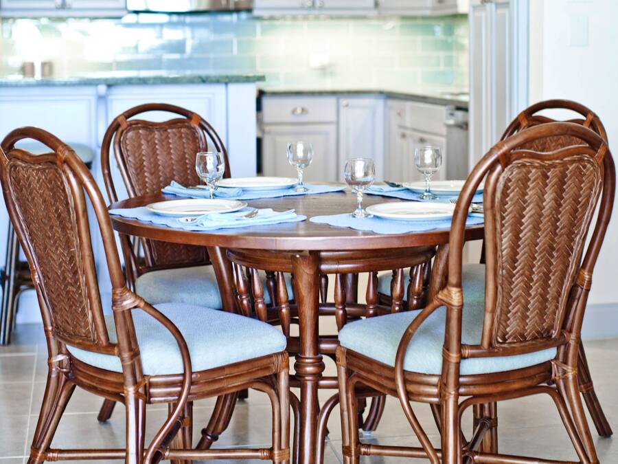 A dining area with a round table, four chairs, and a chandelier.