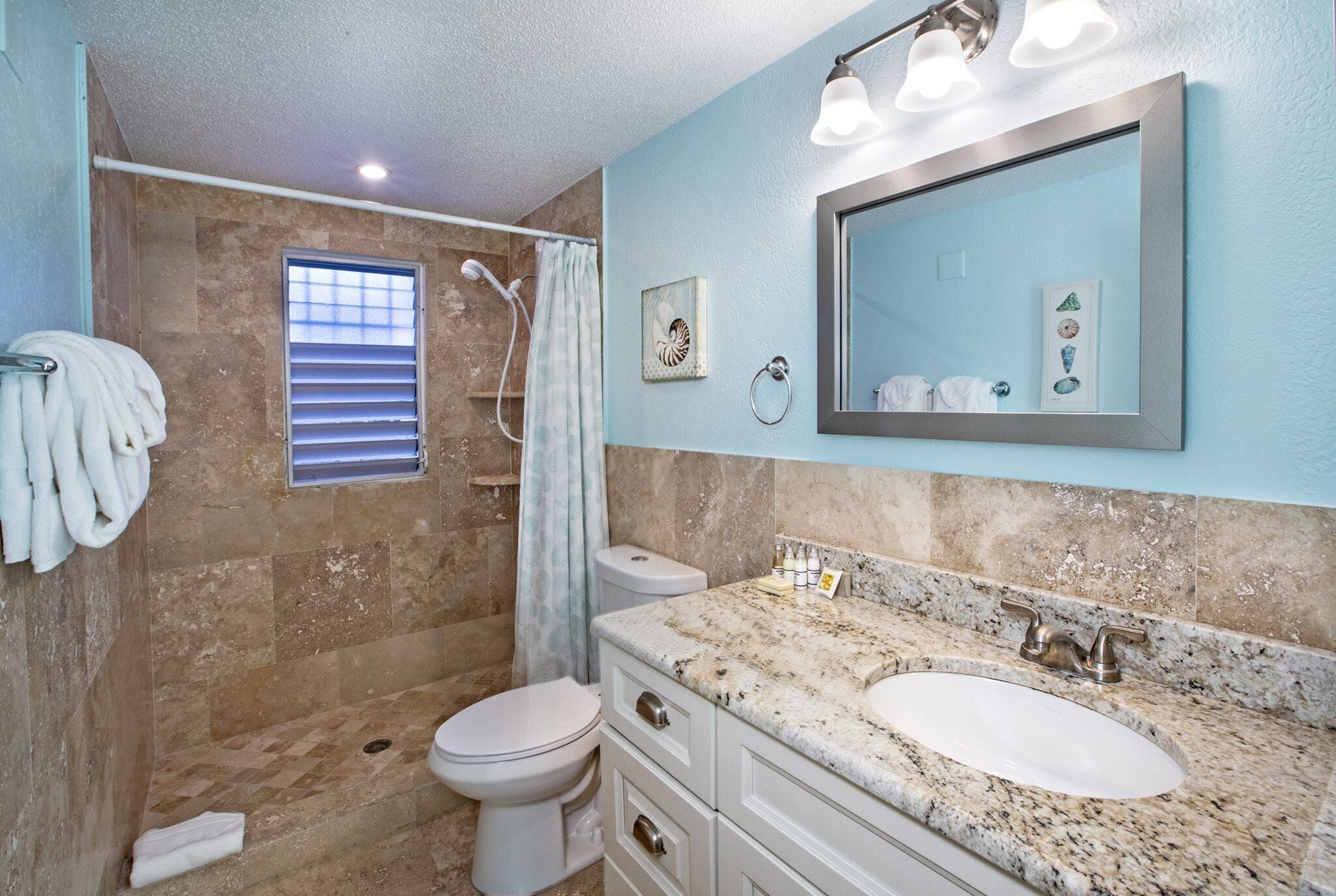 A bathroom with a marble sink, a large mirror, and a shower.