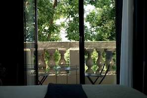 A balcony with a bed, two chairs, and a small table. - Terrass'' Hotel (Paris)