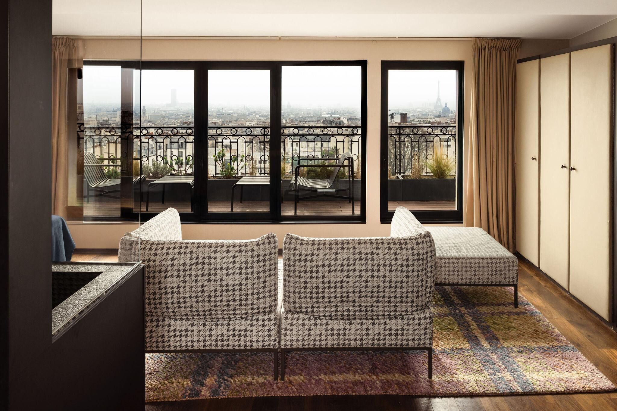A balcony with a view of the city, featuring two patterned sofas and a small table.