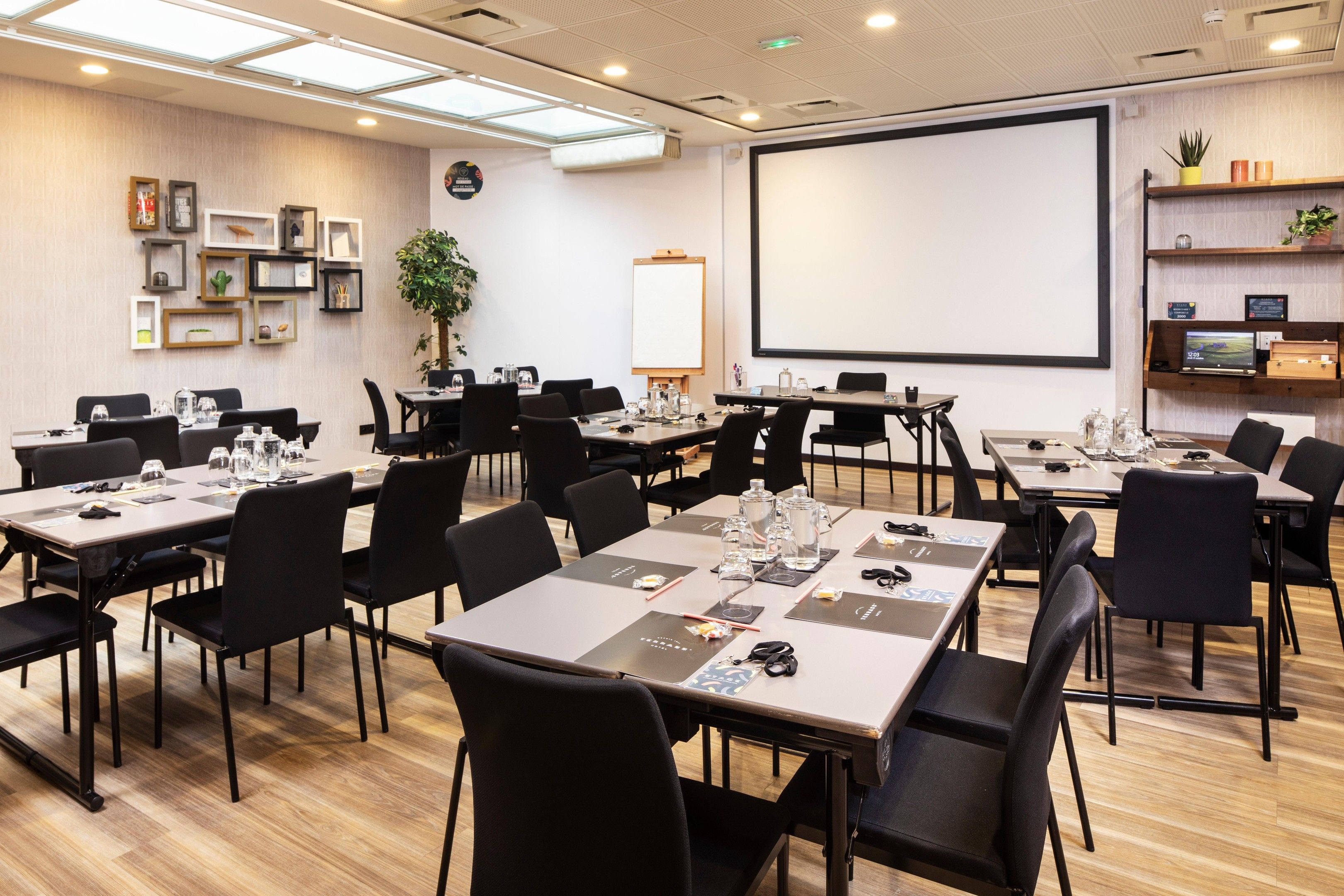 A conference room with tables, chairs, a projector screen, and a whiteboard.