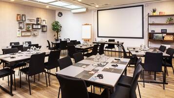 A conference room with tables, chairs, a projector screen, and a whiteboard.