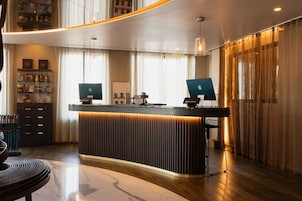 A modern reception desk with two monitors, a glass display case, and a wooden floor.