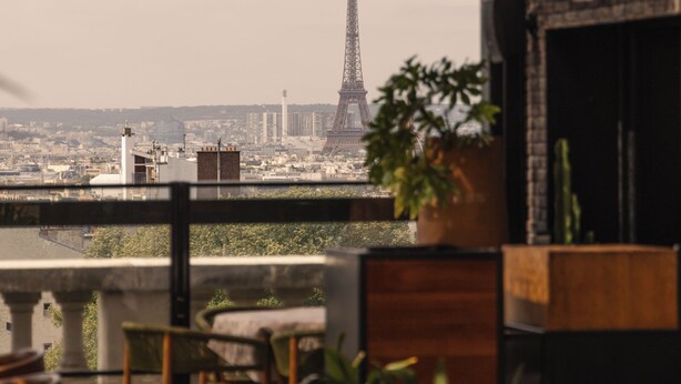 Una terraza en la azotea con vistas a la Torre Eiffel, mobiliario exterior y plantas en macetas.