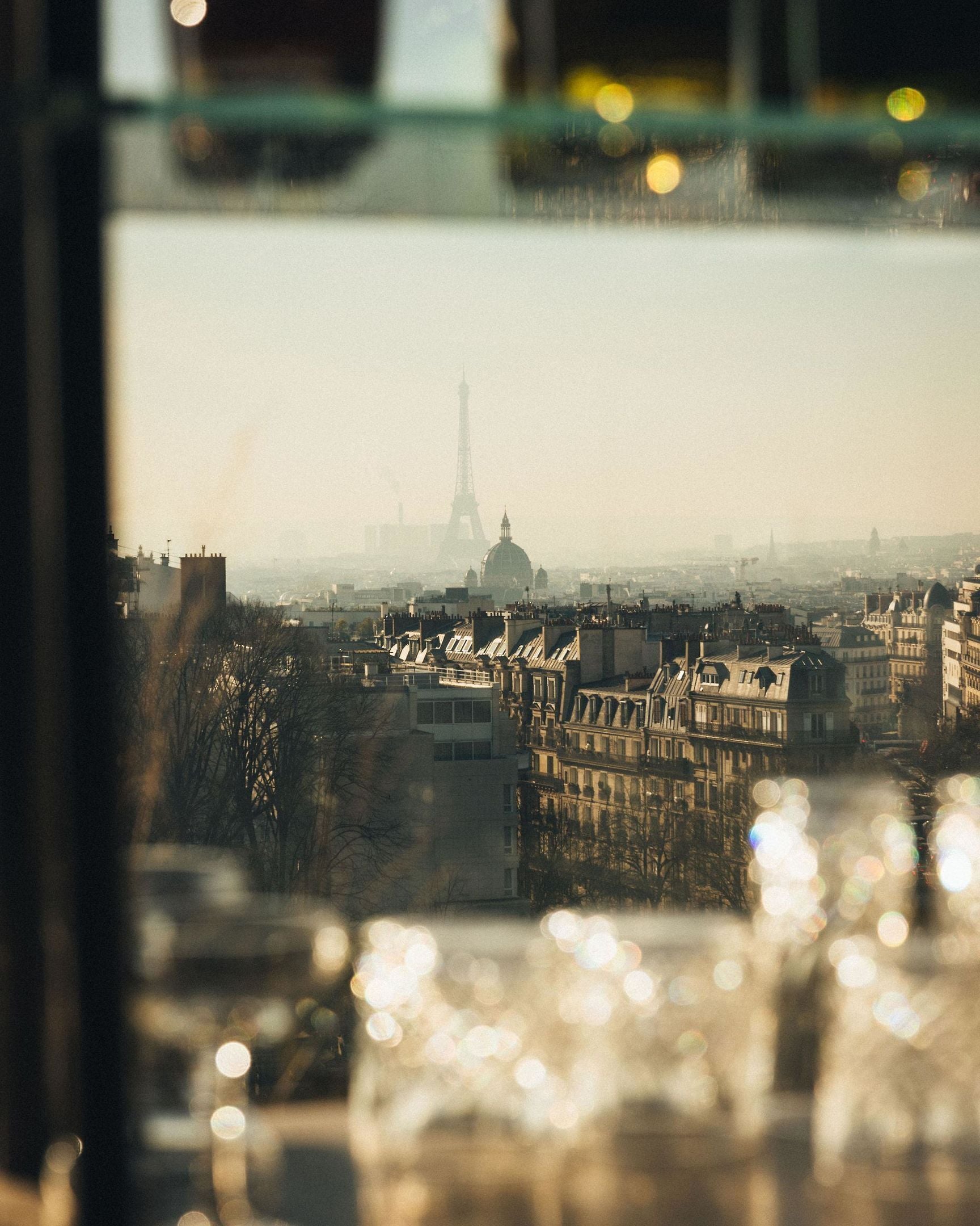 Vista de París desde una ventana, que incluye la Torre Eiffel y edificios circundantes.
