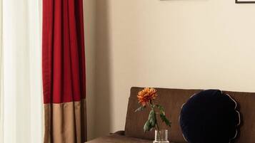Una sala de estar moderna con un sofá marrón, una mesa de centro negra y un florero con una flor. Hay dos cuadros en la pared.
