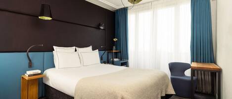 Une chambre d’hôtel avec un grand lit, des tables de chevet, une chaise et un bureau.