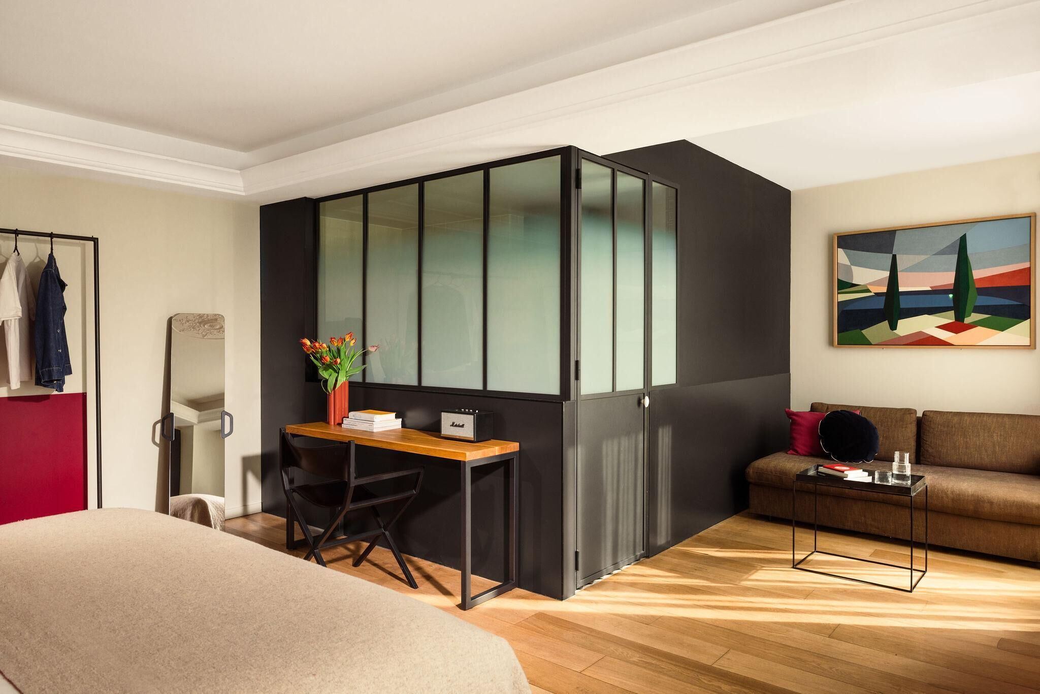 Un dormitorio moderno con cama, escritorio, silla, sofá y un cuadro en la pared.