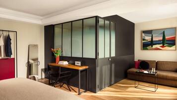Un dormitorio moderno con cama, escritorio, silla, sofá y un cuadro en la pared.