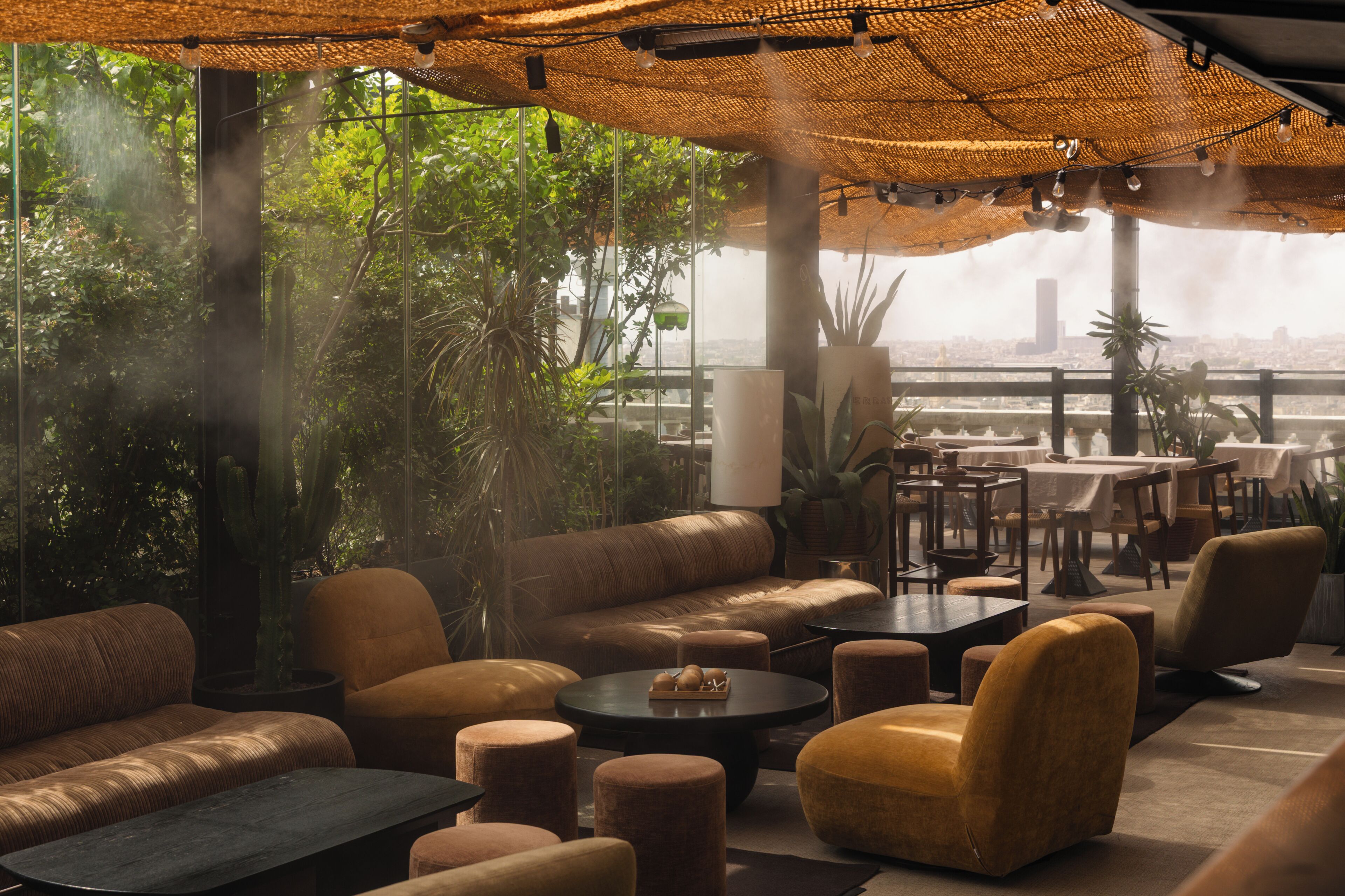 Een terras met buitenmeubels, banken, tafels en potplanten.