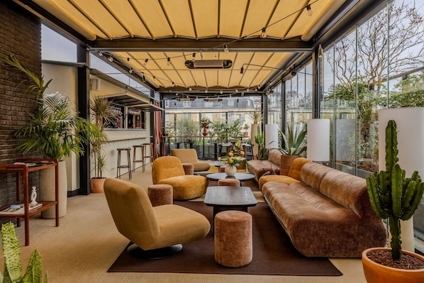 A modern outdoor lounge area with comfortable seating, potted plants, and a view of the cityscape. - Terrass'' Hotel (Paris)