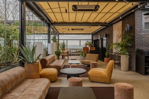 A modern lounge area with sofas, tables, and potted plants. - Terrass'' Hotel (Paris)