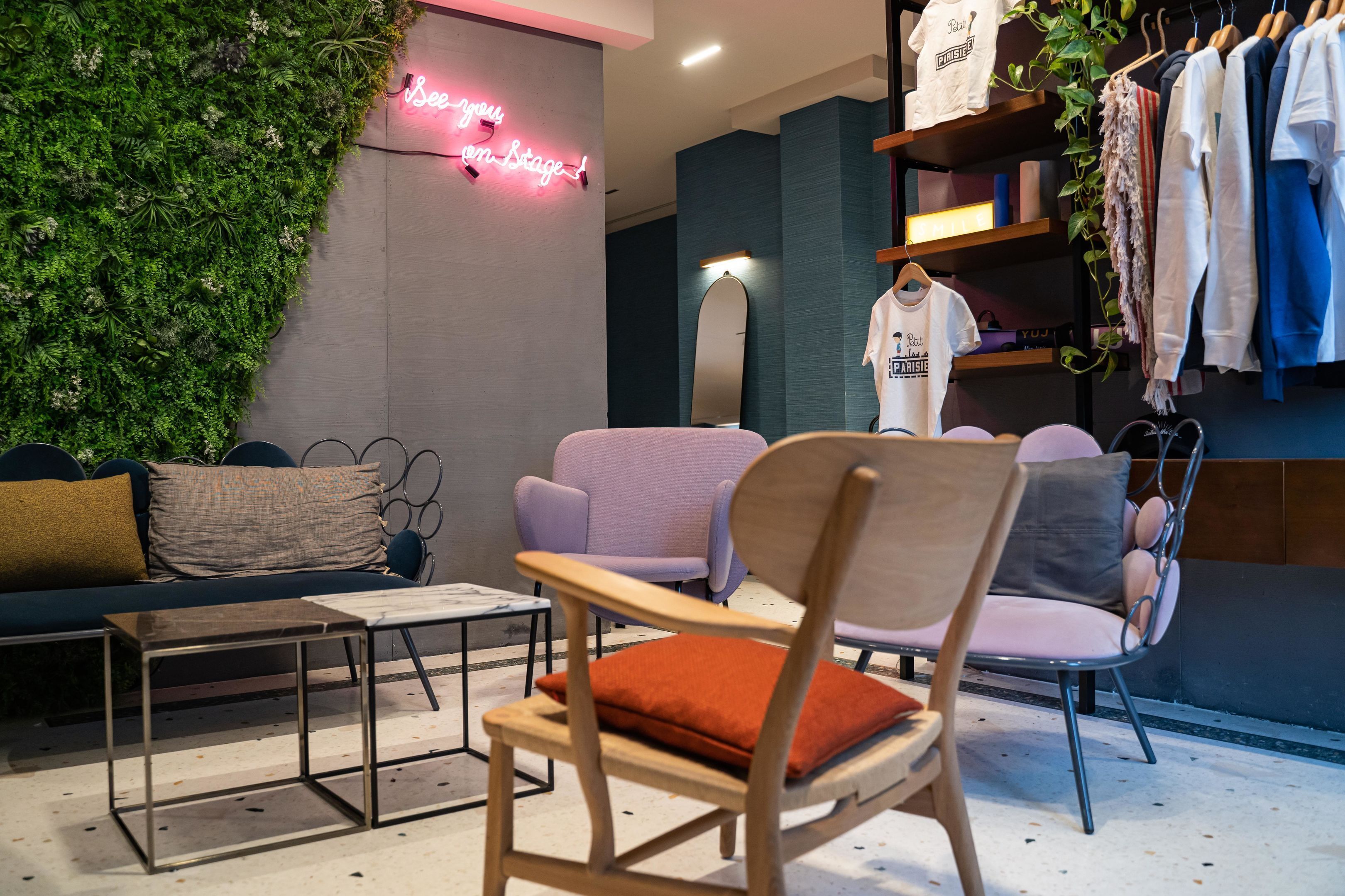 A modern interior with a green wall, seating area, and clothing racks.