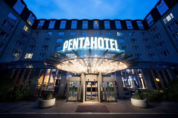 Experience the sleek, modern design of the Pentahotel, featuring a striking glass entrance and illuminated canopy.