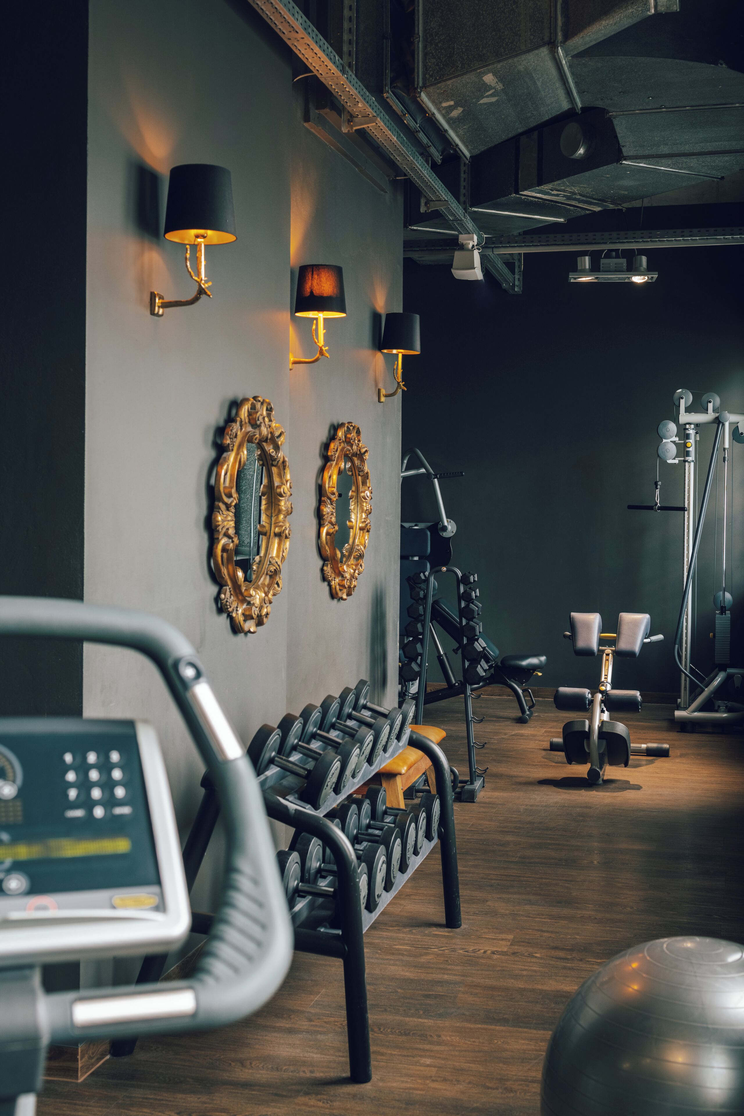 A gym with exercise equipment, a treadmill, and wall-mounted lights.