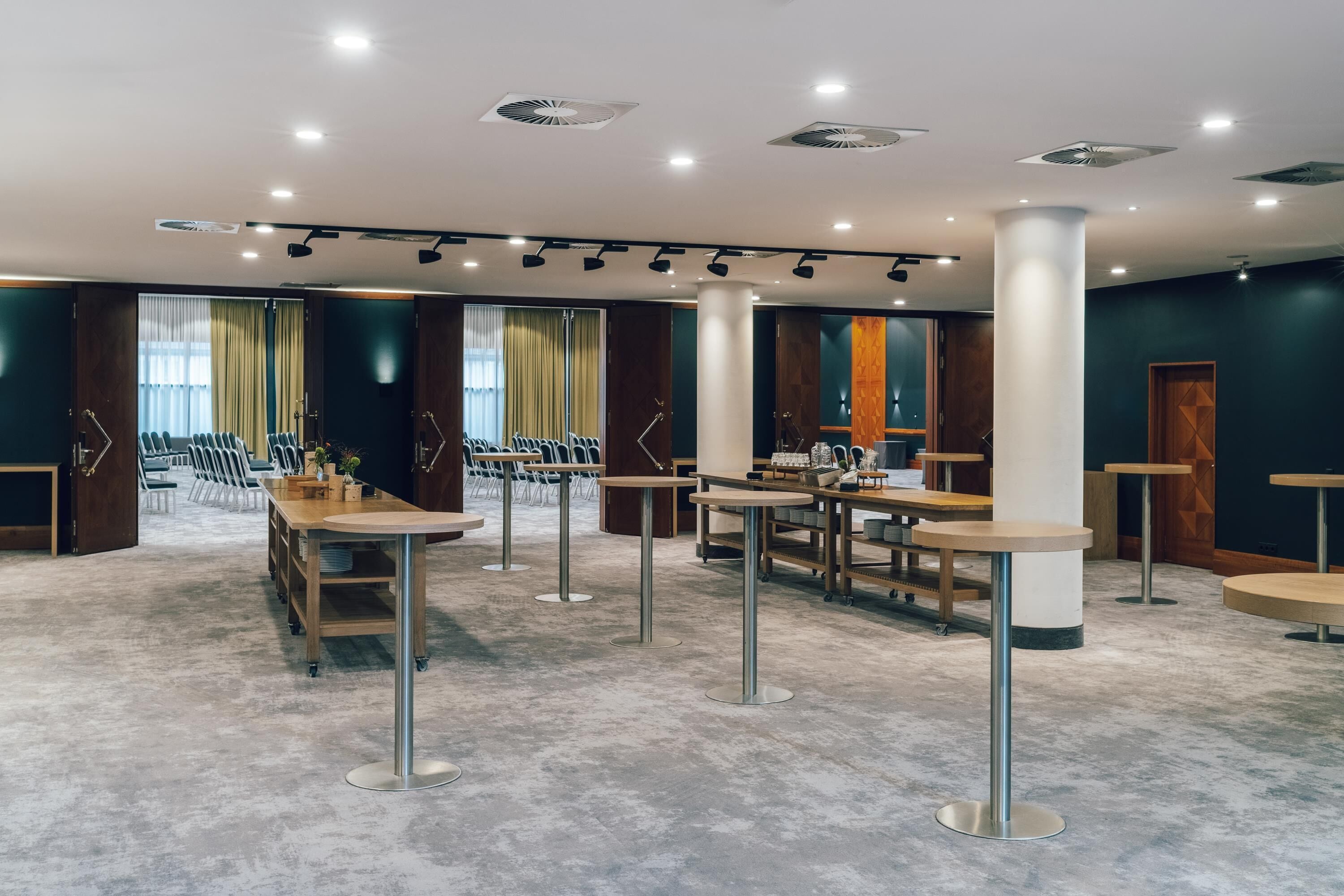 A modern conference room with rows of chairs, tables, and a stage area.