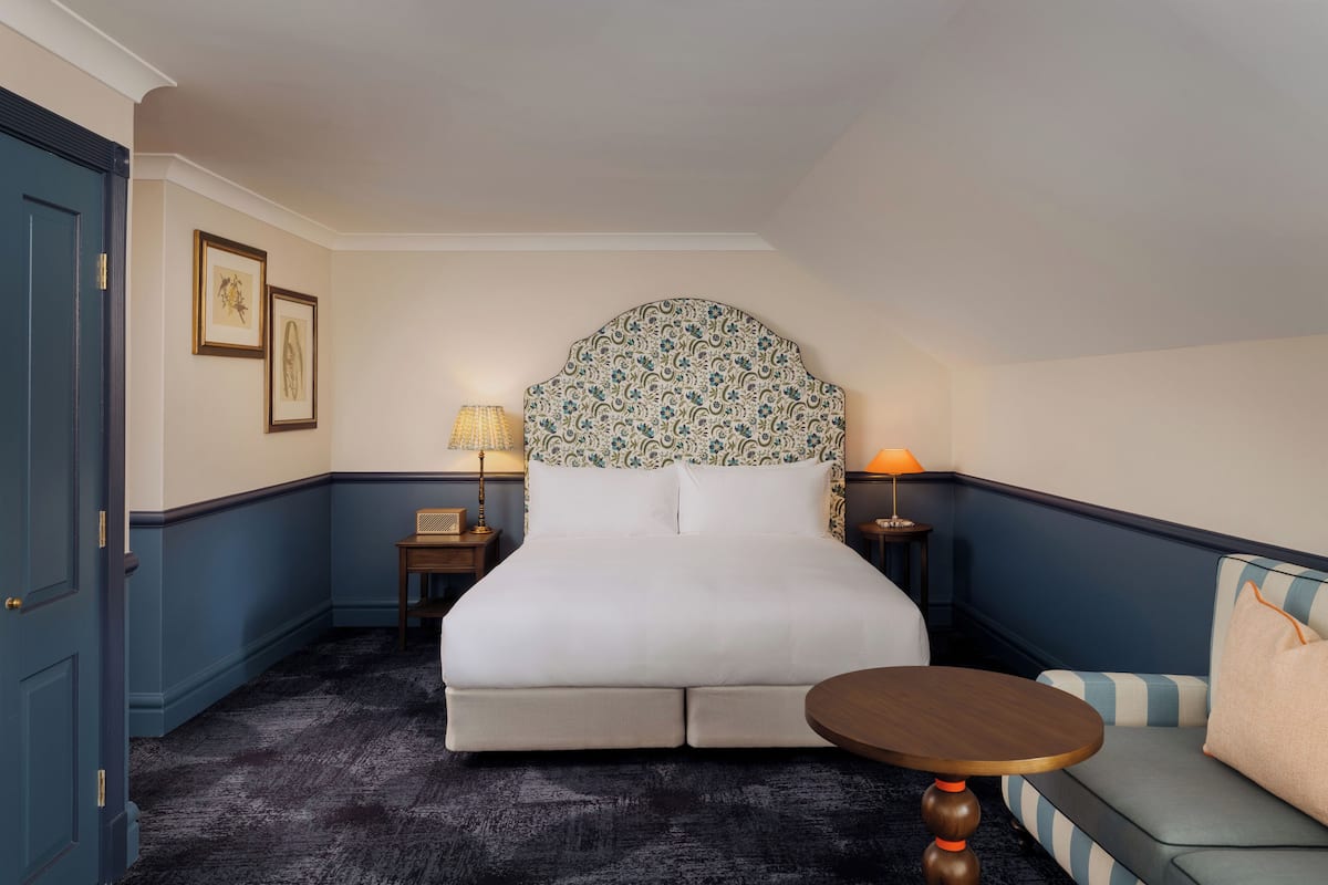 A hotel room with a large bed, two bedside tables, a sofa, and a round table.