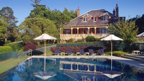 Une grande maison avec une piscine, entourée d’arbres et d’une clôture.