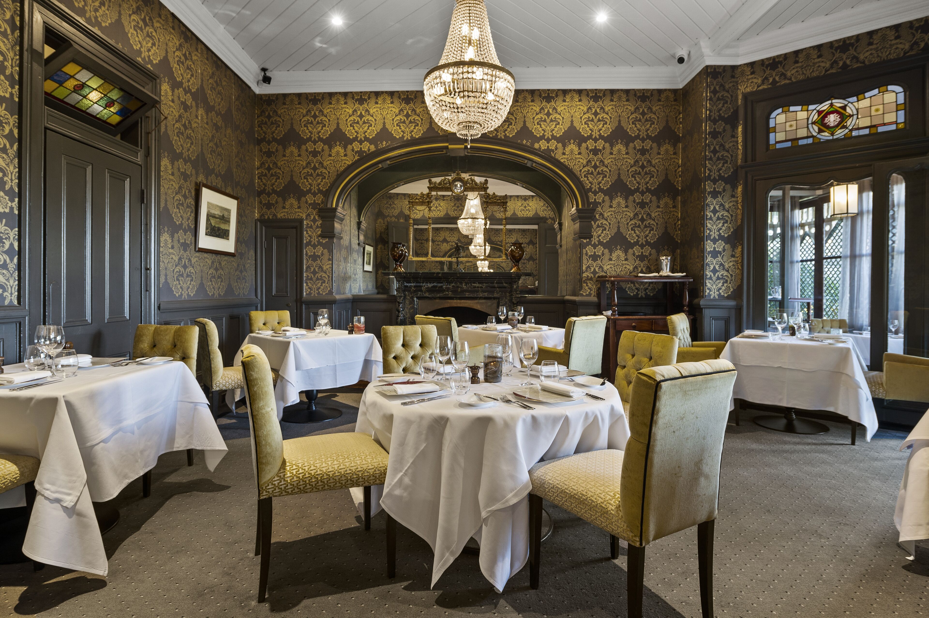 A dining area with round tables, chairs, and a chandelier.