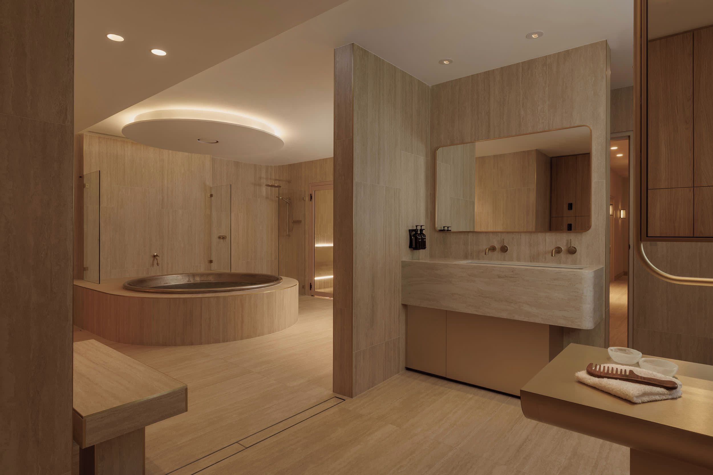 Een moderne badkamer met een vrijstaand bad, een grote spiegel en een wastafel met handdoek en borstel.