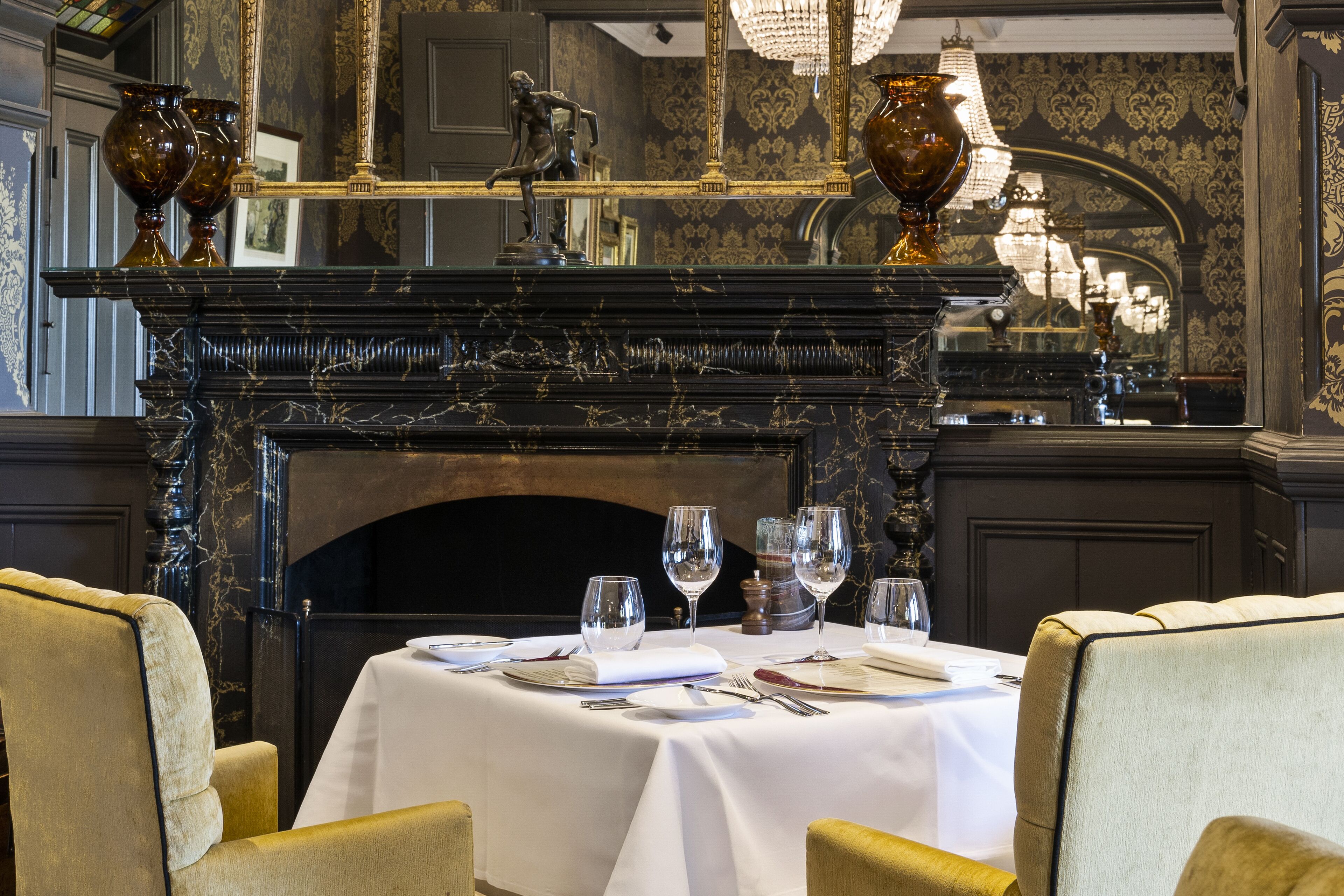 Un coin repas agrémenté d’une cheminée, d’une décoration raffinée et d’une table mise pour le repas.