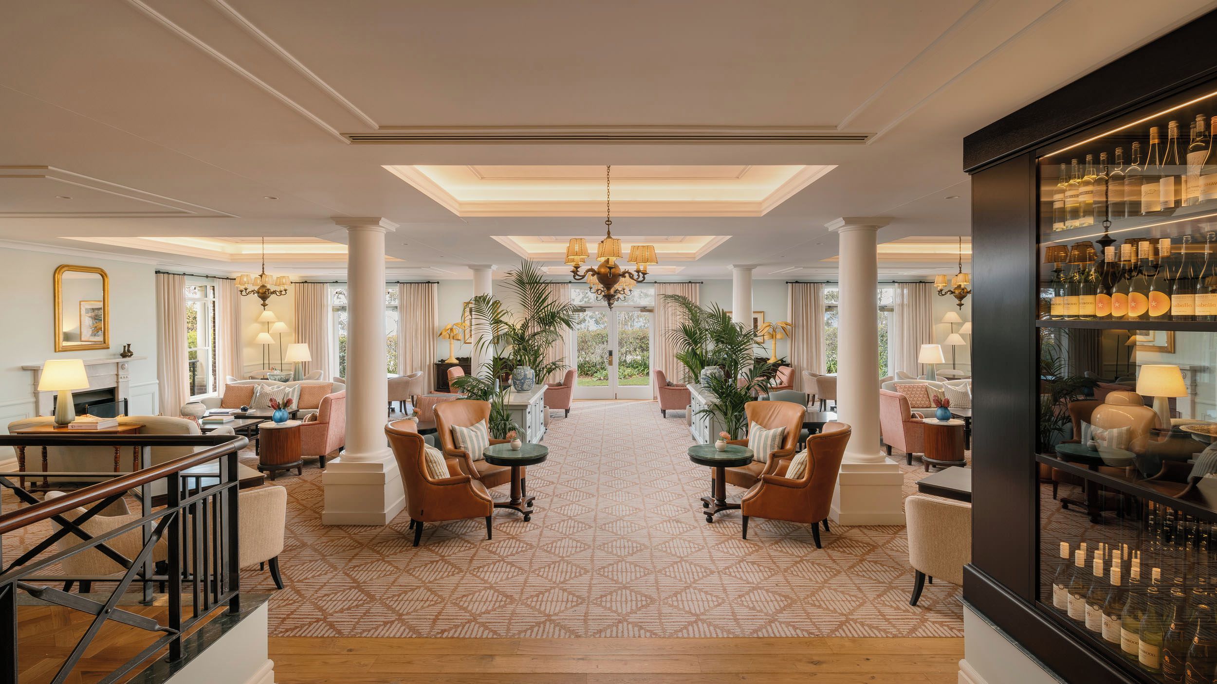 A spacious hotel lobby with a central seating area, large windows, and a wine display.