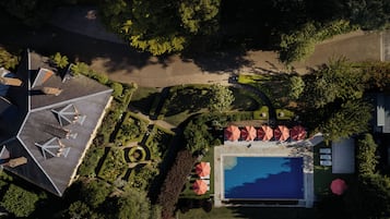 Ein Luftbild eines Resorts mit Schwimmbad, Liegestühlen und einem gepflegten Garten.
