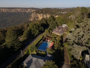 Vista aérea de una extensa propiedad con piscina, varias construcciones y abundante vegetación.
