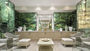 Une salle de bain moderne avec un grand miroir, un meuble-lavabo et un coin salon comprenant des chaises et une table.