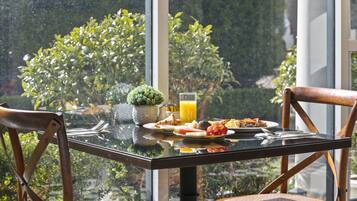 A breakfast table with plates of food, a glass of orange juice, and a small potted plant.