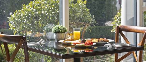 A breakfast table with plates of food, a glass of orange juice, and a small potted plant.