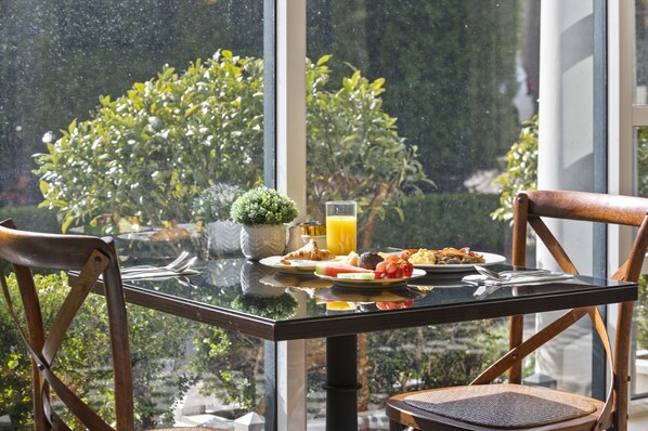A breakfast table with plates of food, a glass of orange juice, and a small potted plant. - Ardour Lilianfels Blue Mountains (Katoomba)