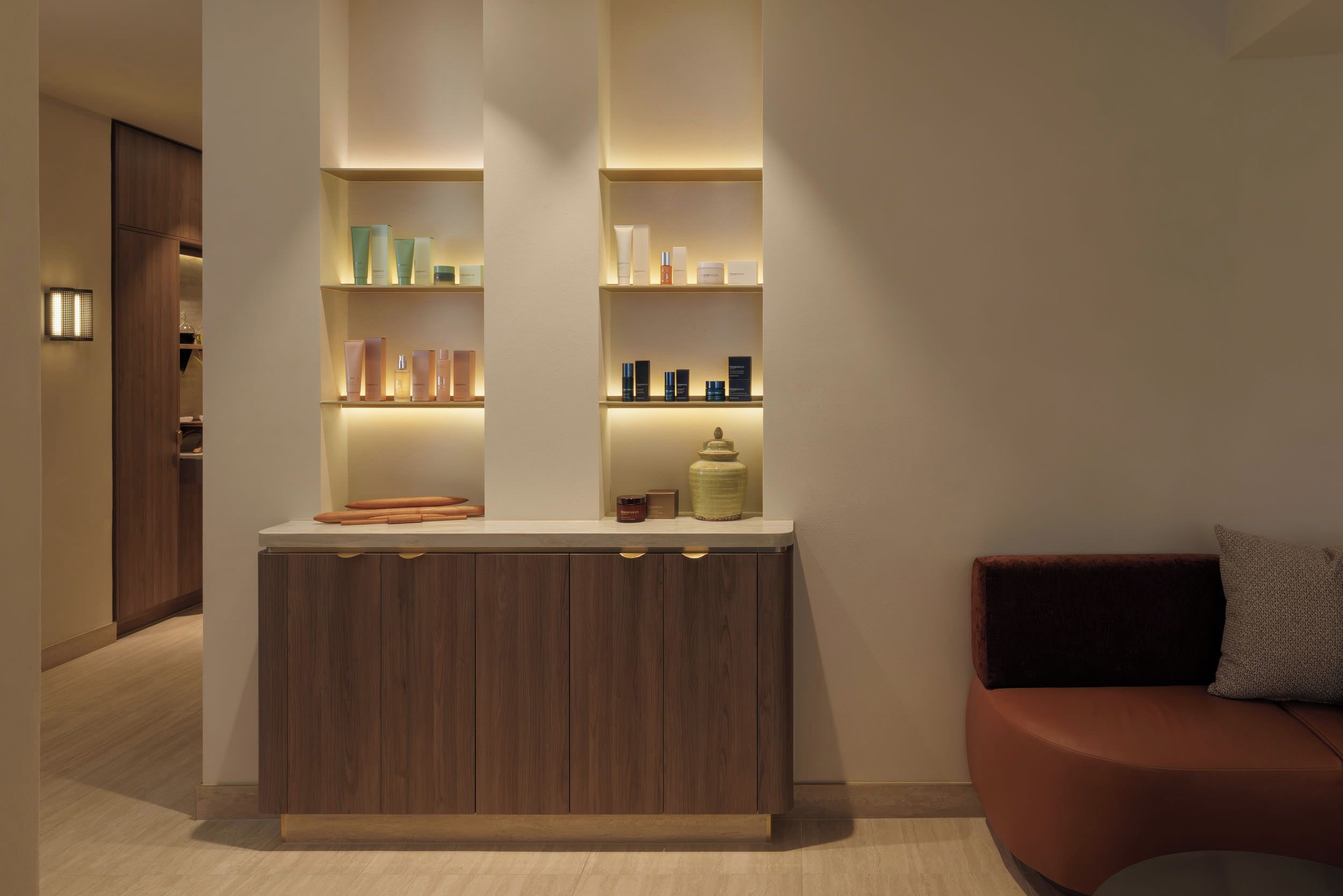 A modern interior with a wooden cabinet and shelves displaying various items.