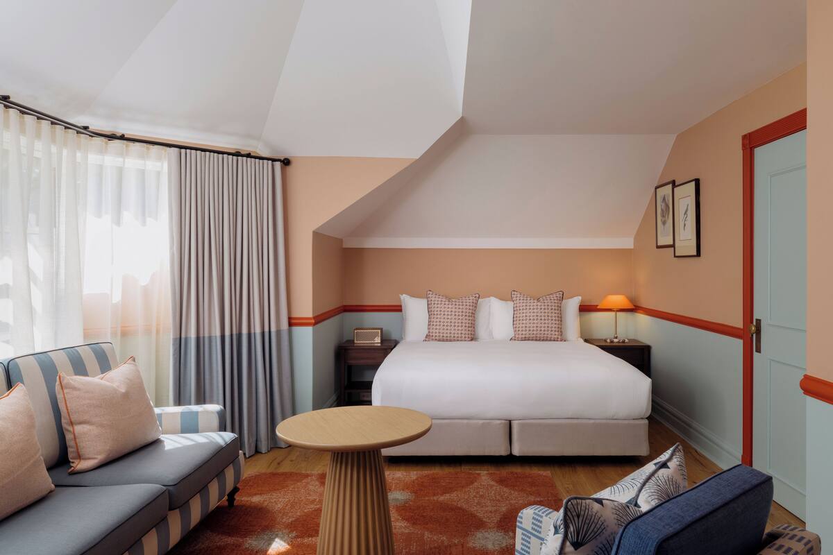 A hotel room with a bed, a sofa, a table, and a nightstand.