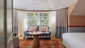 A room with a bed, a sofa, a table, and a view of trees through large windows. - Ardour Lilianfels Blue Mountains (Katoomba)