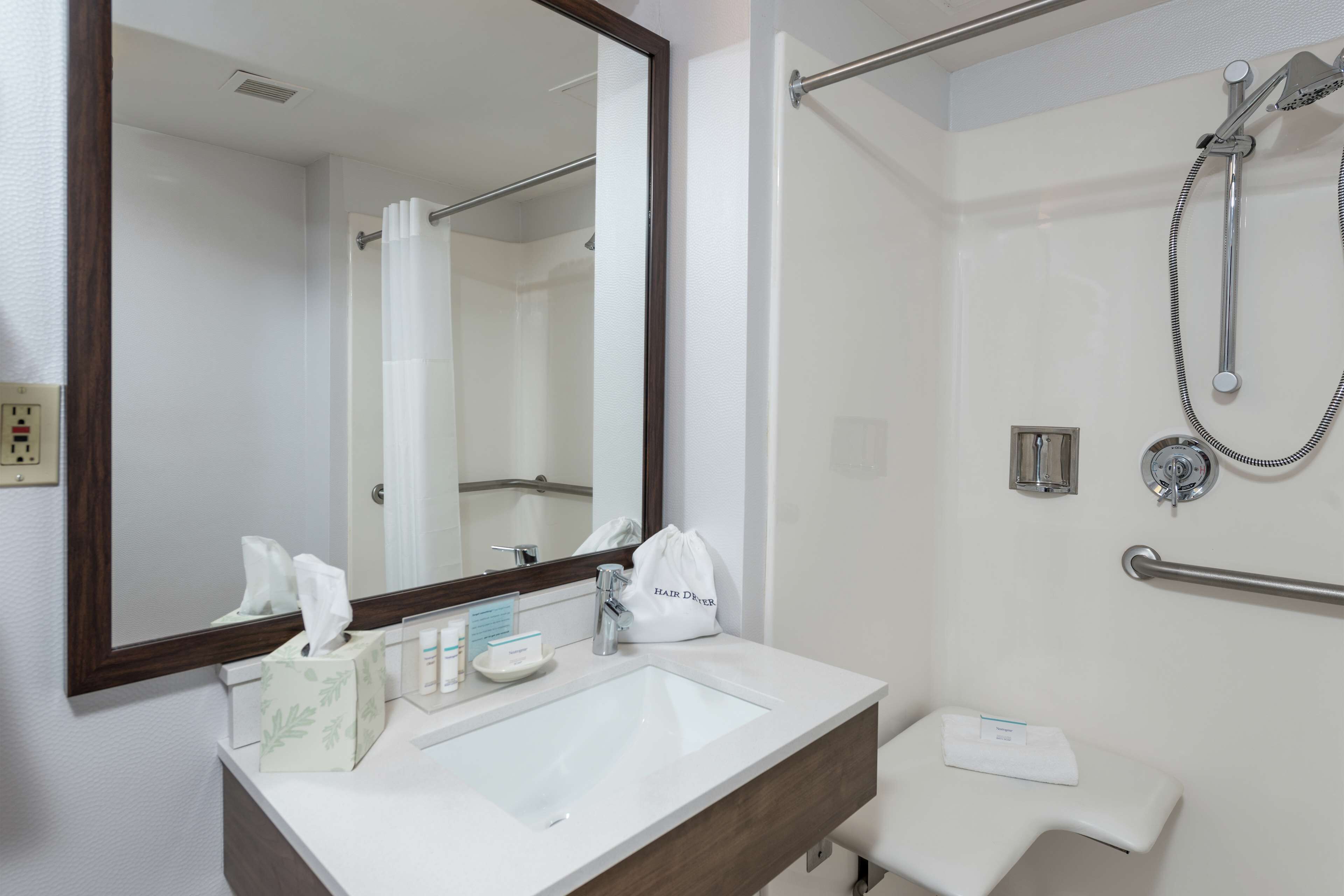 A bathroom with a white sink, mirror, and shower.