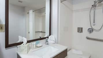 A bathroom with a white sink, mirror, and shower.