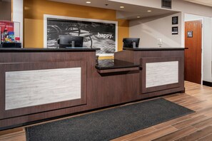 A reception desk with a 'happy' sign, a wooden floor, and a black mat in front.