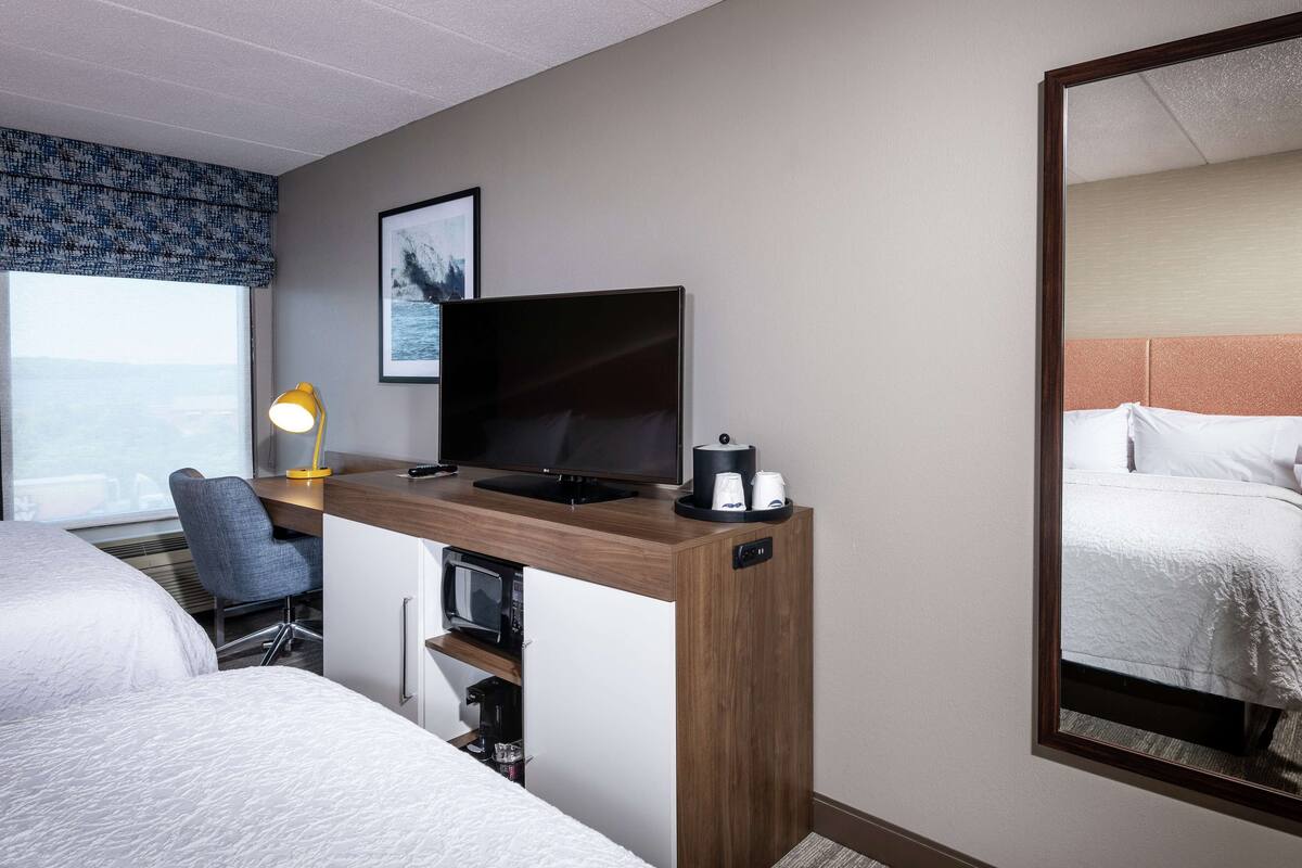 Hotellihuone, jossa on työpöytä, televisio ja sänky.