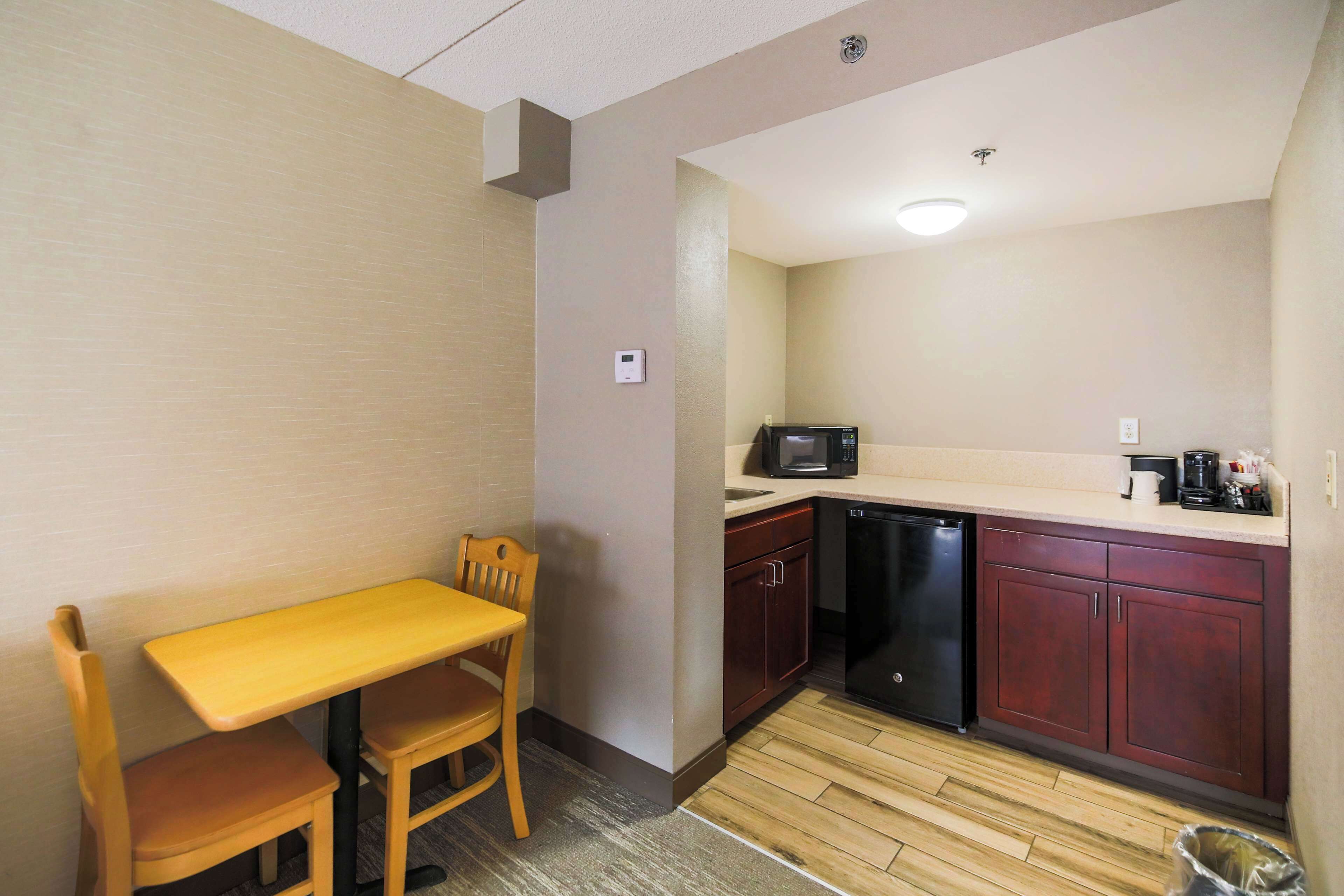 A compact kitchen with a wooden table and chairs, a microwave, and a dishwasher.