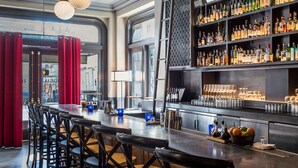 A bar area with a long counter, multiple stools, hanging spherical light fixtures, and a well-stocked bar with various bottles and glasses.