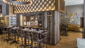A restaurant interior with wooden tables, chairs, and a decorative wall with hexagonal patterns.
